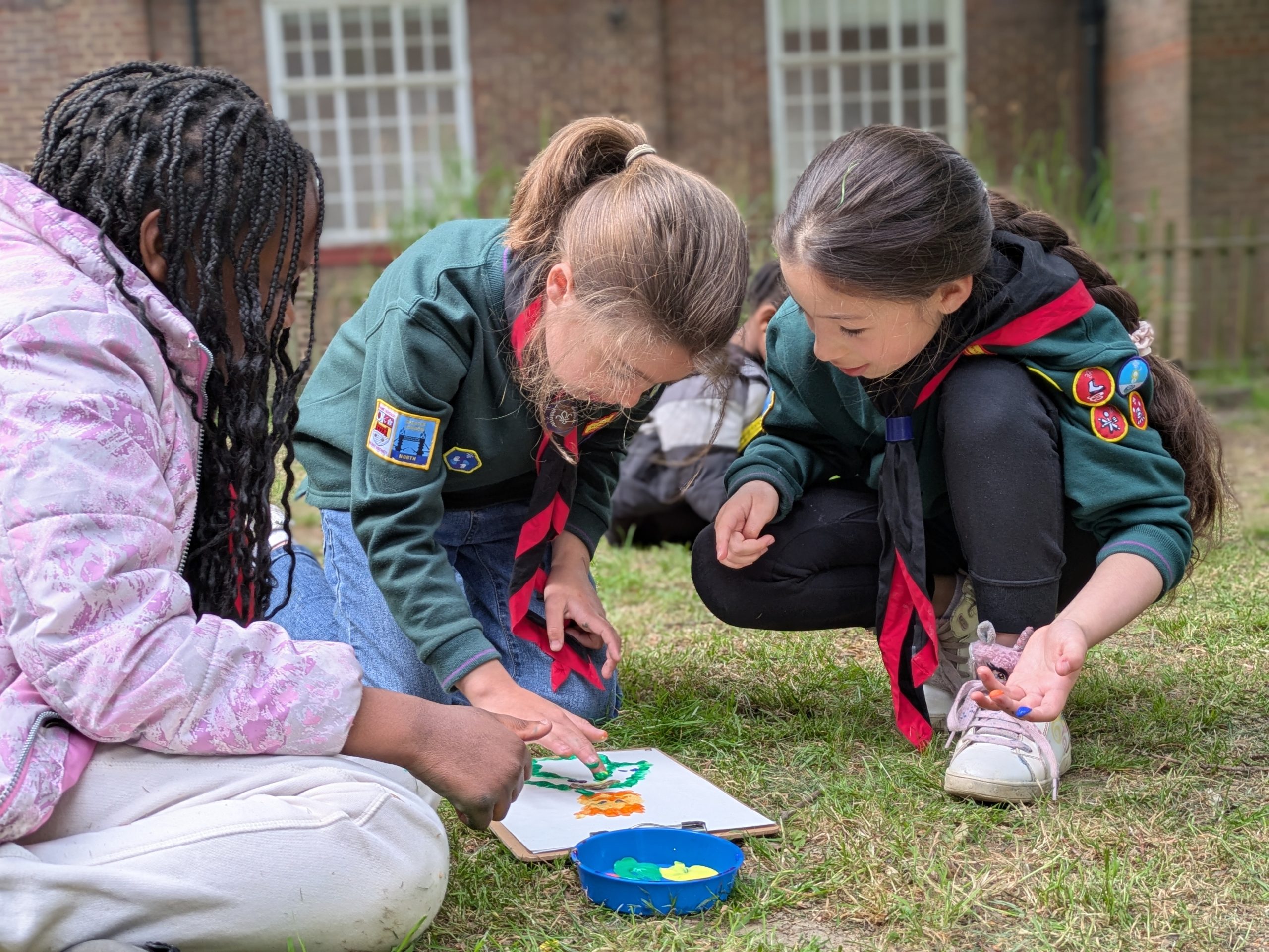 A group of Cub Scouts finger painting outdoors in Edgware