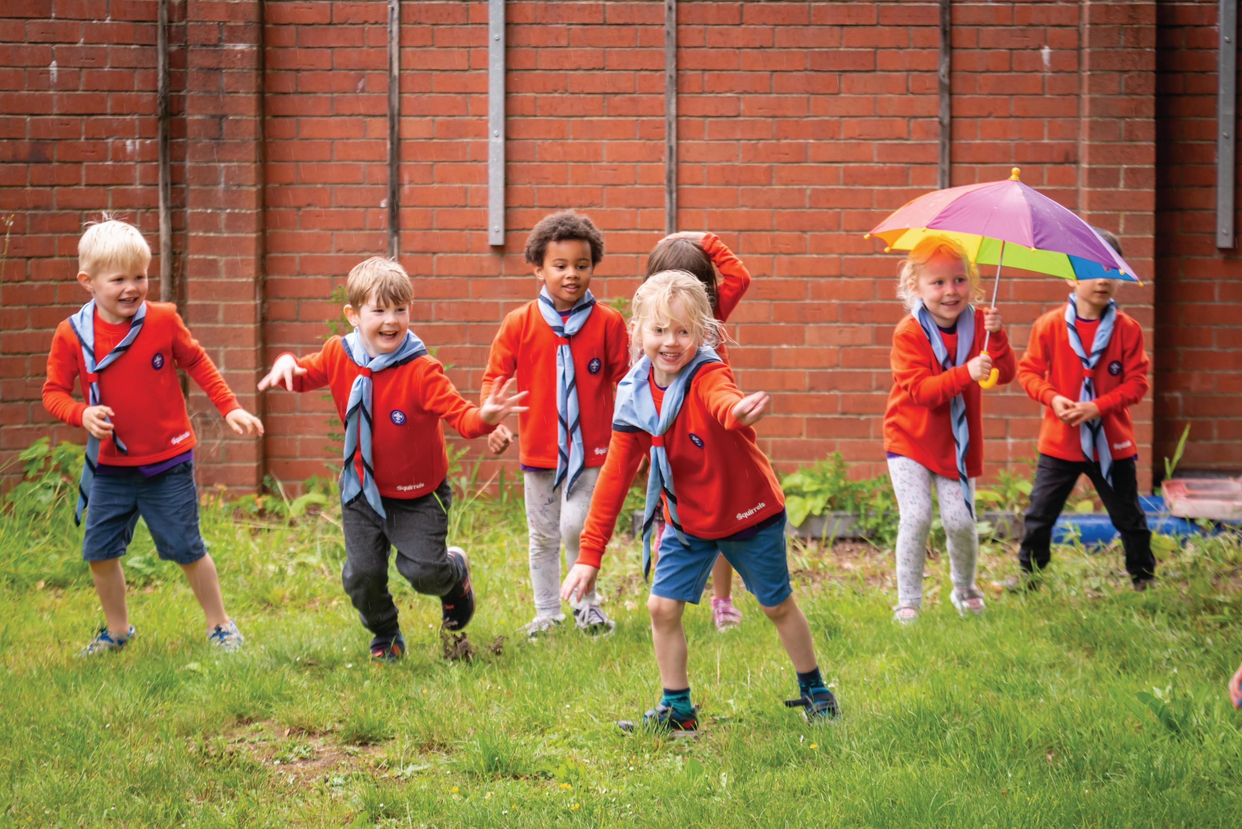 A group of Squirrel Scouts wearing their red jumpers, playing outdoors